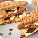 Chocolover’s Erdnussbutter- Banana-Sandwich      Zutaten:  Für die Erdnussbutter: 150 g geröstete, ungesalzene Erdnusskerne, 20 g Vollrohrzucker, 1 TL Kokosöl, 1 Msp. Vanilleextrakt, 1 Prise feines Meersalz  Für die Schokotäfelchen: 75 g Zartbitterschokolade (mind. 70 %)  Für das Sandwich: 1 kleine Banane 8 Scheiben Vollkornsandwichbrot  Außerdem: Back- oder Pergamentpapier      Zubereitung:  Die Erdnüsse in eine Küchenmaschine oder einen Standmixer geben und 2–3 Minuten mixen bis eine glatte, cremige Masse entstanden ist. Den Vollrohrzucker, das Kokosöl, den Vanilleextrakt und das Salz zufügen und nochmals etwa 1 Minute mixen, bis sich alle Komponenten gut verbunden haben. Die Schokolade grob hacken und über einem heißen Wasserbad vorsichtig schmelzen. Ein glattes Stück Back- oder Pergamentpapier auf einem großen Brett auslegen, die Schokolade darauf gießen und mit einem Löffel oder einer Winkelpalette glatt und dünn verstreichen. Das Brett für etwa 15 Minuten in den Kühlschrank stellen. Die Schokolade mit einem Pizzaschneider oder scharfen Messer in Rechtecke schneiden. Falls noch einige Stellen der Schokolade zu weich sind, nochmals in den Kühlschrank stellen und dann den Rest in Rechtecke schneiden. Die Banane schälen und in dünne Scheiben schneiden. Die Brotscheiben rösten und die Hälfte der Brotscheiben mit Erdnussbutter bestreichen. Die Bananenscheiben und Schokotäfelchen auf den Brotscheiben verteilen, mit den übrigen Brotscheiben abdecken, diagonal halbieren und servieren.      Mehr Rezepte finden Sie in in: Sporternährung für jeden Tag, 240 Seiten, 29,99 Euro