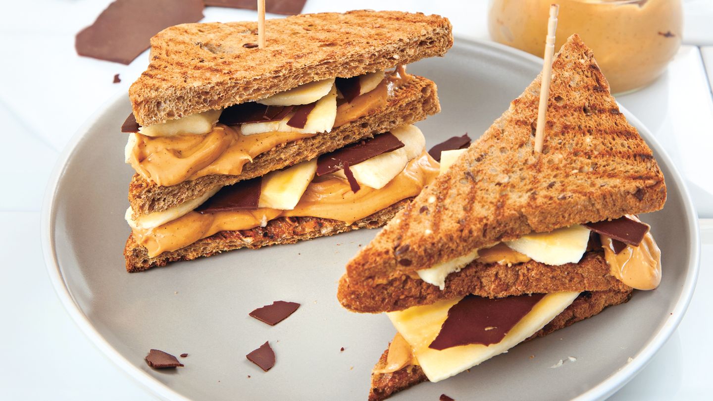 Bewusst essen: Chocolover’s Erdnussbutter- Banana-Sandwich Zutaten: Für die Erdnussbutter: 150 g geröstete, ungesalzene Erdnusskerne, 20 g Vollrohrzucker, 1 TL Kokosöl, 1 Msp. Vanilleextrakt, 1 Prise feines Meersalz Für die Schokotäfelchen: 75 g Zartbitterschokolade (mind. 70 %) Für das Sandwich: 1 kleine Banane 8 Scheiben Vollkornsandwichbrot Außerdem: Back- oder Pergamentpapier Zubereitung: Die Erdnüsse in eine Küchenmaschine oder einen Standmixer geben und 2–3 Minuten mixen bis eine glatte, cremige Masse entstanden ist. Den Vollrohrzucker, das Kokosöl, den Vanilleextrakt und das Salz zufügen und nochmals etwa 1 Minute mixen, bis sich alle Komponenten gut verbunden haben. Die Schokolade grob hacken und über einem heißen Wasserbad vorsichtig schmelzen. Ein glattes Stück Back- oder Pergamentpapier auf einem großen Brett auslegen, die Schokolade darauf gießen und mit einem Löffel oder einer Winkelpalette glatt und dünn verstreichen. Das Brett für etwa 15 Minuten in den Kühlschrank stellen. Die Schokolade mit einem Pizzaschneider oder scharfen Messer in Rechtecke schneiden. Falls noch einige Stellen der Schokolade zu weich sind, nochmals in den Kühlschrank stellen und dann den Rest in Rechtecke schneiden. Die Banane schälen und in dünne Scheiben schneiden. Die Brotscheiben rösten und die Hälfte der Brotscheiben mit Erdnussbutter bestreichen. Die Bananenscheiben und Schokotäfelchen auf den Brotscheiben verteilen, mit den übrigen Brotscheiben abdecken, diagonal halbieren und servieren. Mehr Rezepte finden Sie in in: Sporternährung für jeden Tag, 240 Seiten, 29,99 Euro Chocolover’s Erdnussbutter- Banana-Sandwich Zutaten: Für die Erdnussbutter: 150 g geröstete, ungesalzene Erdnusskerne, 20 g Vollrohrzucker, 1 TL Kokosöl, 1 Msp. Vanilleextrakt, 1 Prise feines Meersalz Für die Schokotäfelchen: 75 g Zartbitterschokolade (mind. 70 %) Für das Sandwich: 1 kleine Banane 8 Scheiben Vollkornsandwichbrot Außerdem: Back- oder Pergamentpapier Zubereitung: Die Erdnüsse in eine Küchenmaschine oder einen Standmixer geben und 2–3 Minuten mixen bis eine glatte, cremige Masse entstanden ist. Den Vollrohrzucker, das Kokosöl, den Vanilleextrakt und das Salz zufügen und nochmals etwa 1 Minute mixen, bis sich alle Komponenten gut verbunden haben. Die Schokolade grob hacken und über einem heißen Wasserbad vorsichtig schmelzen. Ein glattes Stück Back- oder Pergamentpapier auf einem großen Brett auslegen, die Schokolade darauf gießen und mit einem Löffel oder einer Winkelpalette glatt und dünn verstreichen. Das Brett für etwa 15 Minuten in den Kühlschrank stellen. Die Schokolade mit einem Pizzaschneider oder scharfen Messer in Rechtecke schneiden. Falls noch einige Stellen der Schokolade zu weich sind, nochmals in den Kühlschrank stellen und dann den Rest in Rechtecke schneiden. Die Banane schälen und in dünne Scheiben schneiden. Die Brotscheiben rösten und die Hälfte der Brotscheiben mit Erdnussbutter bestreichen. Die Bananenscheiben und Schokotäfelchen auf den Brotscheiben verteilen, mit den übrigen Brotscheiben abdecken, diagonal halbieren und servieren. Mehr Rezepte finden Sie in in: Sporternährung für jeden Tag, 240 Seiten, 29,99 Euro