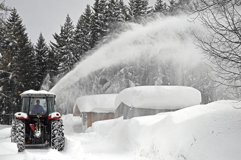 Ein Schneepflug räumt Schnee von einer Straße im österreichischen Ramsau Am Dachstein