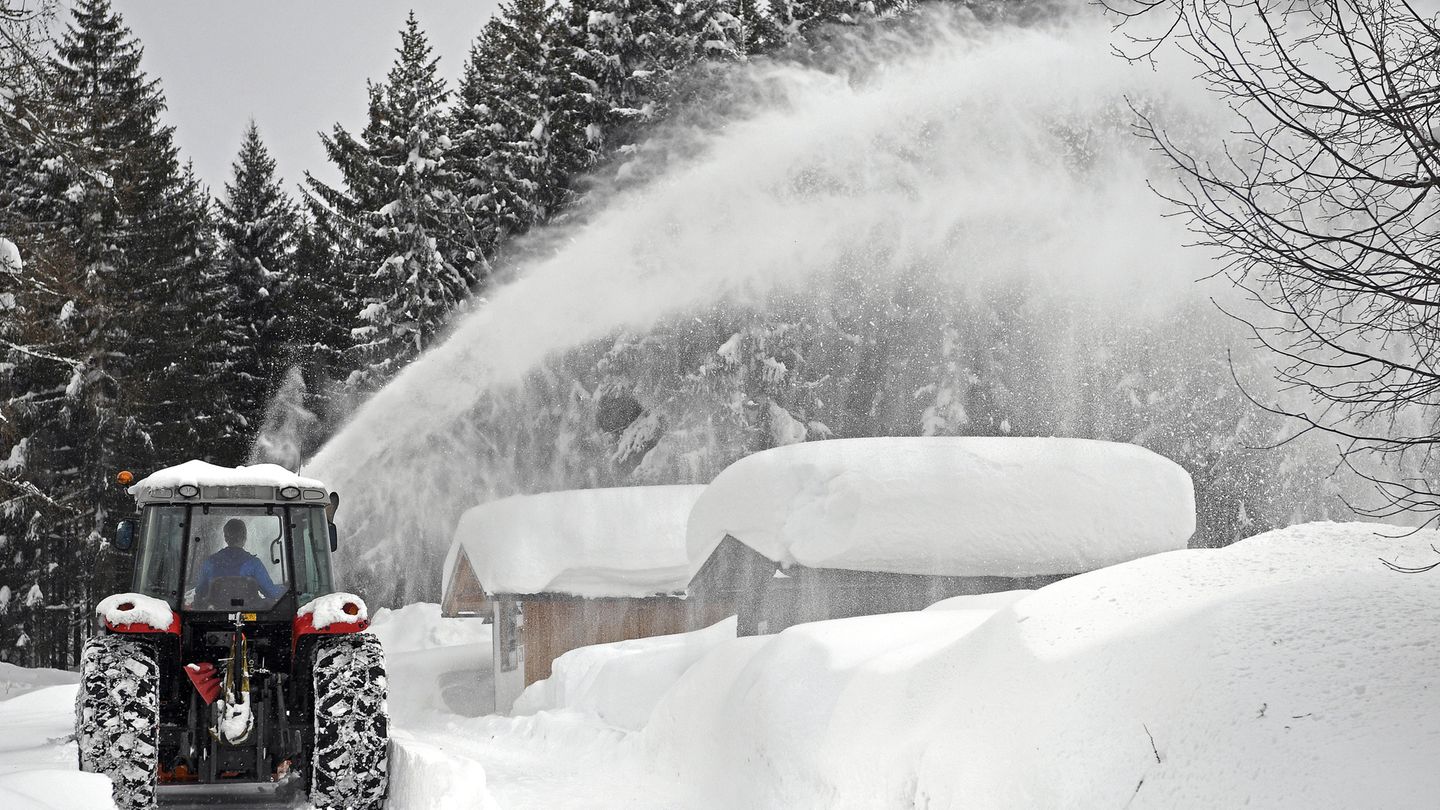 Ein Schneepflug räumt Schnee von einer Straße im österreichischen Ramsau Am Dachstein