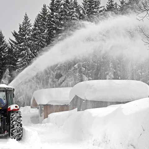Ein Schneepflug räumt Schnee von einer Straße im österreichischen Ramsau Am Dachstein