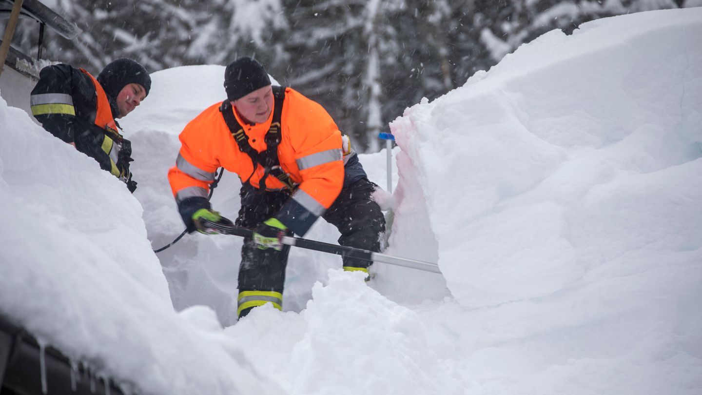  Bayern, Buchenhöhe. Feuerwehrmänner schaufeln Schnee vom Dach eines Hauses. Nach starkem Schneefall sitzen bei Berchtesgaden rund 350 Menschen fest und müssen per Lastwagen mit Lebensmitteln versorgt werden.