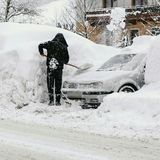 Österreich, Saalbach. Ein Mann schaufelt sein Auto auf einem Parkplatz frei. Immer mehr Touristen sitzen fest. Wie schon am Mittwoch sind die beliebten Reiseziele Obertauern, Lech, Zürs und Hallstatt weiter nicht zu erreichen.