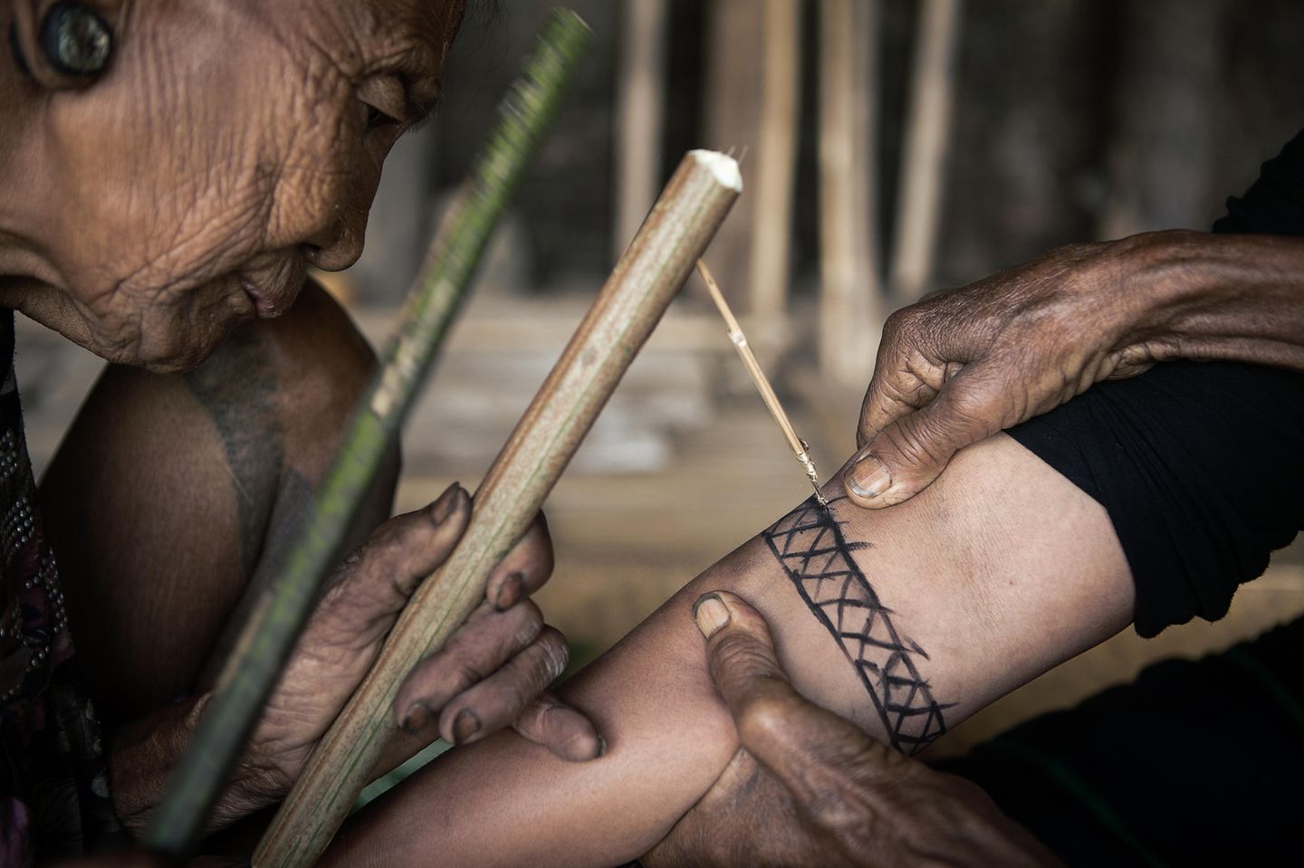 Mit Bambushölzern wird das Tattoo in die Haut geklopft