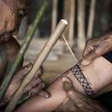 Mit Bambushölzern wird das Tattoo in die Haut geklopft