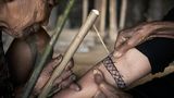 Mit Bambushölzern wird das Tattoo in die Haut geklopft