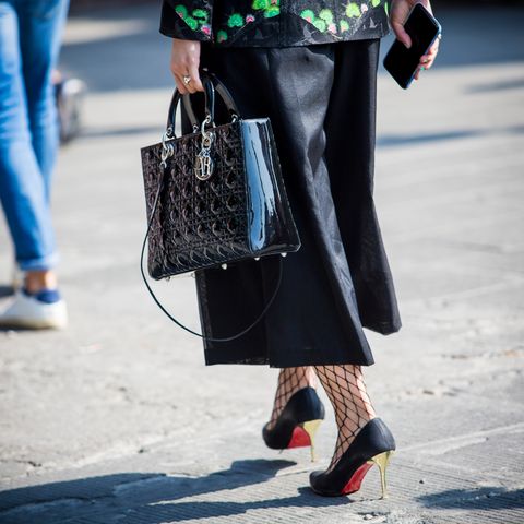 Frau in Culotte und High-Heels läuft über die Straße