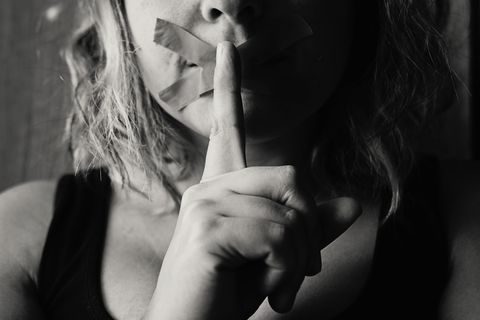 Frau hält sich Finger vor den Mund