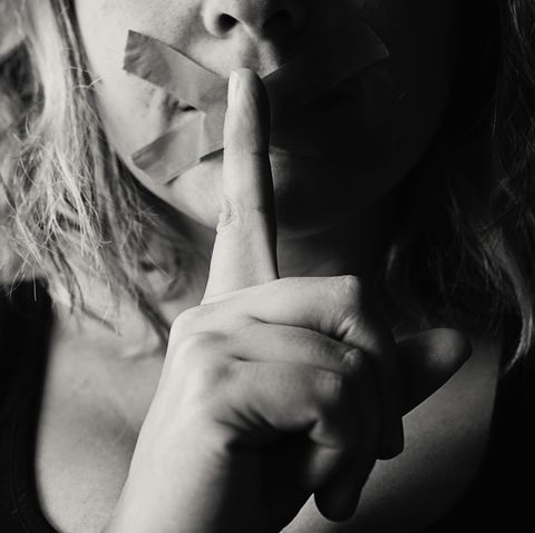 Frau hält sich Finger vor den Mund