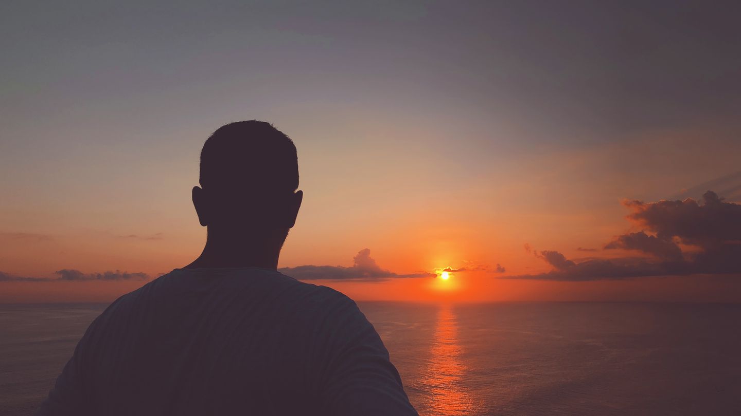 Mann am Meer mit Sonnenuntergang