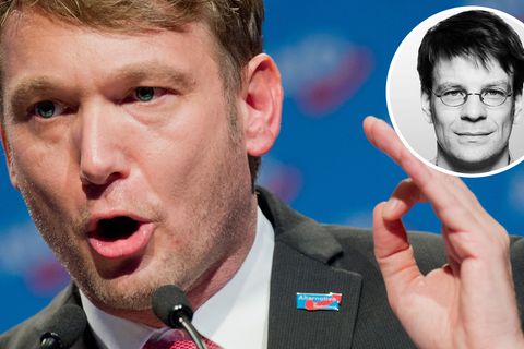 André Poggenburg steht am Rednerpult und gestikuliert mit seiner linken Hand