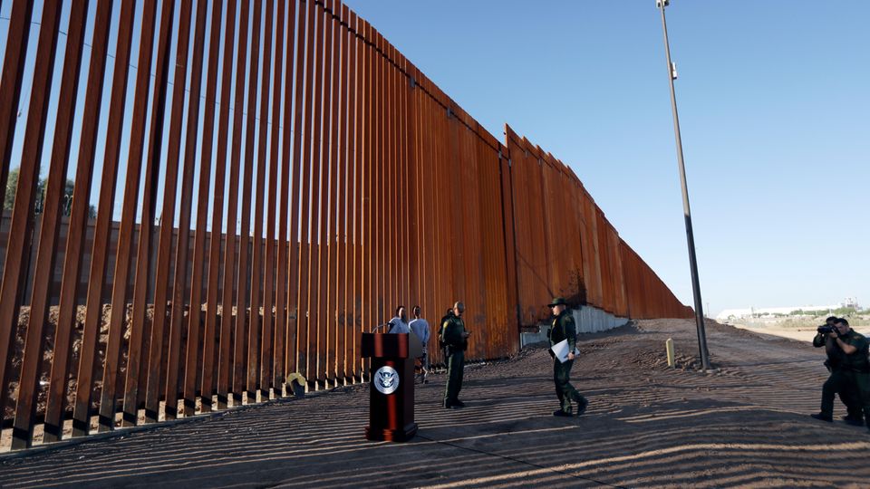 USA, Calexico: Grenzschutzbeamte stehen neben einem neuen Abschnitt der Grenzmauer zwischen den USA und Mexiko