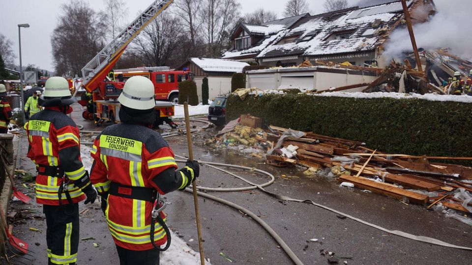 Feuerwehrleute stehen bei einem zerstörten Reihenhaus