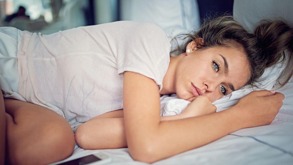 Depression Eine Frau liegt traurig im Bett