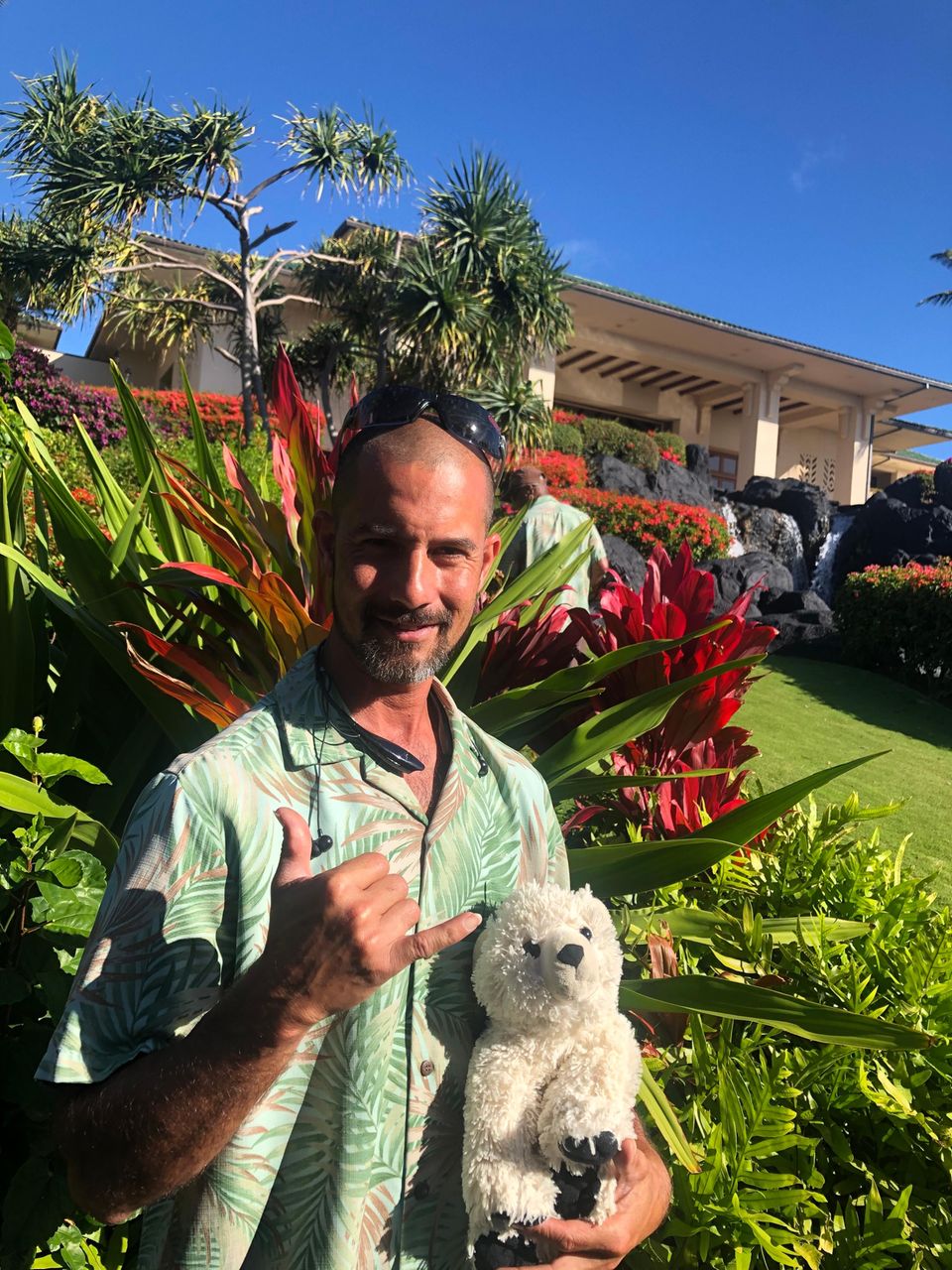 Teddy vergessen Der Landschaftgärtner des Hotels grüßt in die Kamera – mit dem Teddy auf dem Arm