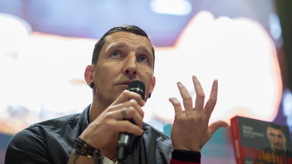 Ex-Handballer Stefan Kretzschmar sitzt auf einer Bühne und spricht in ein Mikro in seiner rechten Hand