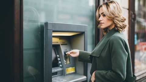 Eine Frau hebt am Geldautomaten Geld ab