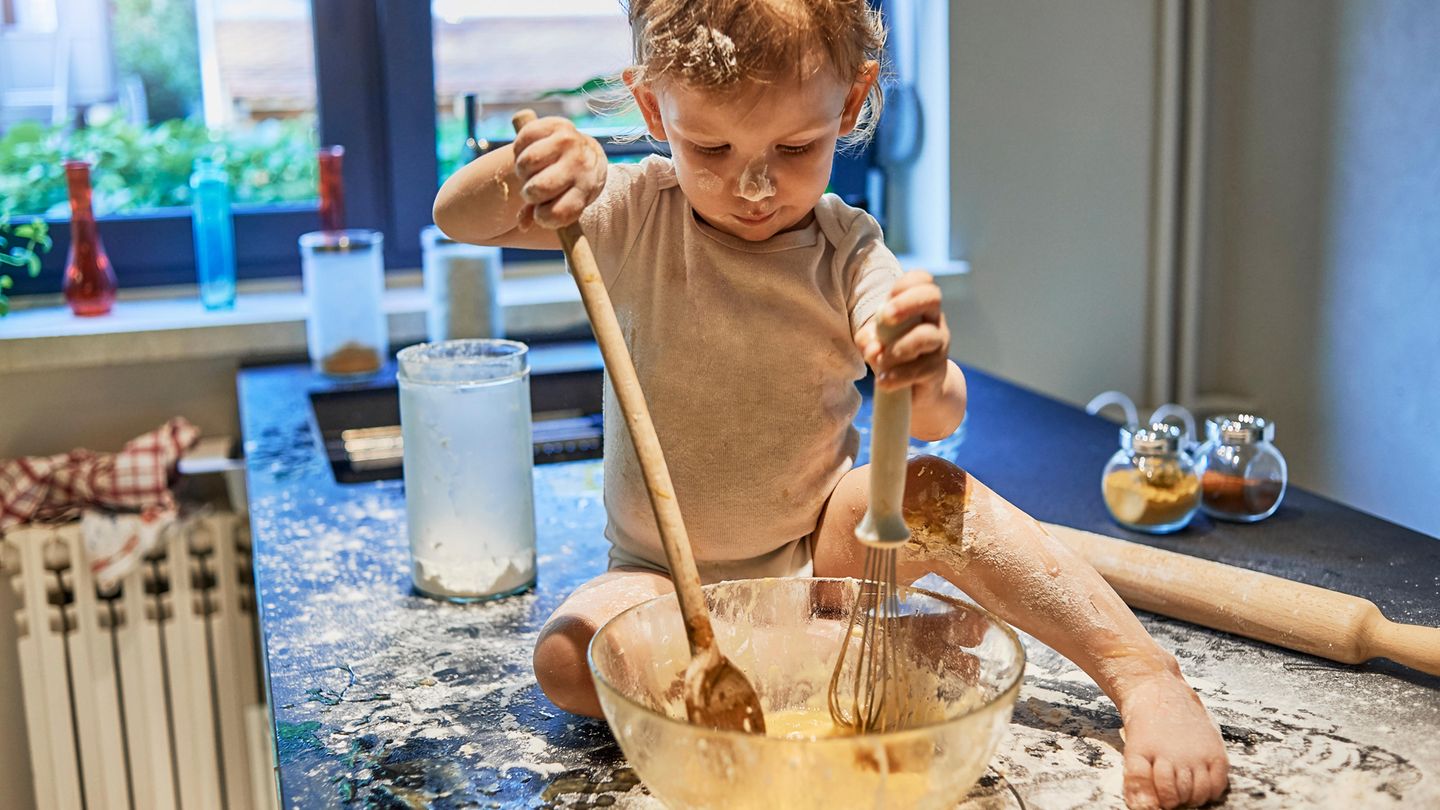 Ein kleiner Junge schmiert mit Mehl und Kuchenteig herum