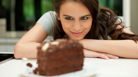 Eine Frau schaut lächelnd ein Stück Schokoladentorte an