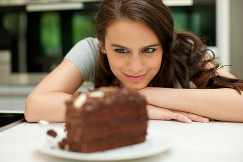 Eine Frau schaut lächelnd ein Stück Schokoladentorte an