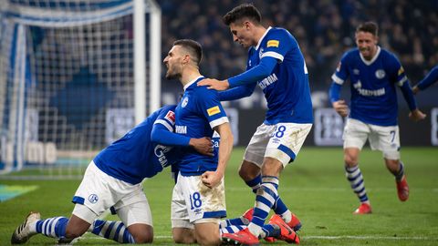 Drei Schalker Spieler knien neben dem Tor und jubeln über einen Treffer