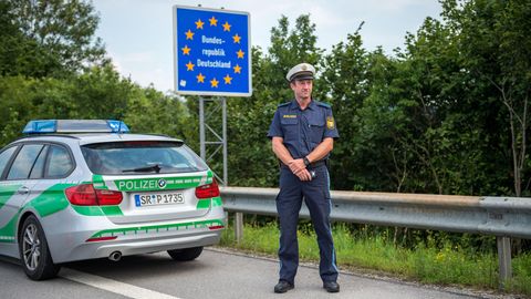 Ein bayerischer Grenzpolizist steht hinter einem BMW-Komb iauf dem Standstreifen