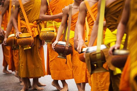 Tagtägliche buddhistische Praxis: der frühmorgendliche Bettelgang Tak Bat. In den  Henkeltöpfen sammeln Mönche Spenden von Gläubigen.