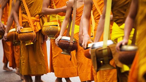 Tagtägliche buddhistische Praxis: der frühmorgendliche Bettelgang Tak Bat. In den  Henkeltöpfen sammeln Mönche Spenden von Gläubigen.