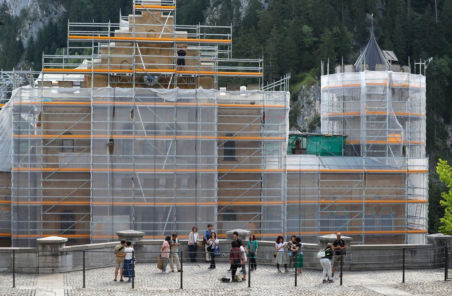Während der Renovierungsphase nicht besonders fotogen: Touristen stehen vor dem eingerüsteten Torhaus von Schloss Neuschwanstein. 