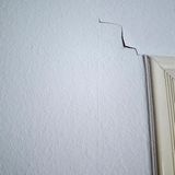 Über einem Türrahmen geht ein Riss durch die Tapete