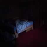 Ein Bett steht in einem abgedunkelten Zimmer