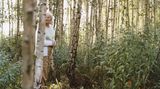 Eine alte Frau steht in einem Birkenwald