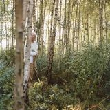 Eine alte Frau steht in einem Birkenwald