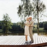 Das alte Ehepaar umarmt sich an einem Fluss stehend