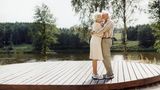Das alte Ehepaar umarmt sich an einem Fluss stehend
