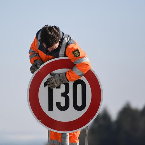 Ein Straßenwärter montiert an der Autobahn A81 am Hegaublick ein Schild mit der Aufschrift «130»