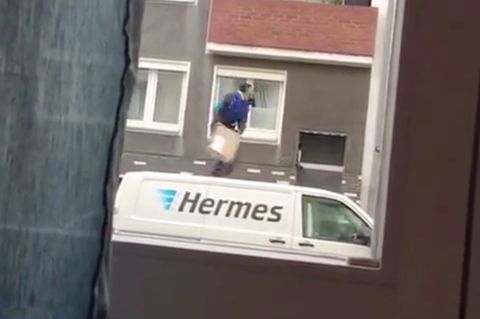 Ein Hermes-Bote wirft ein Paket auf den Balkon.