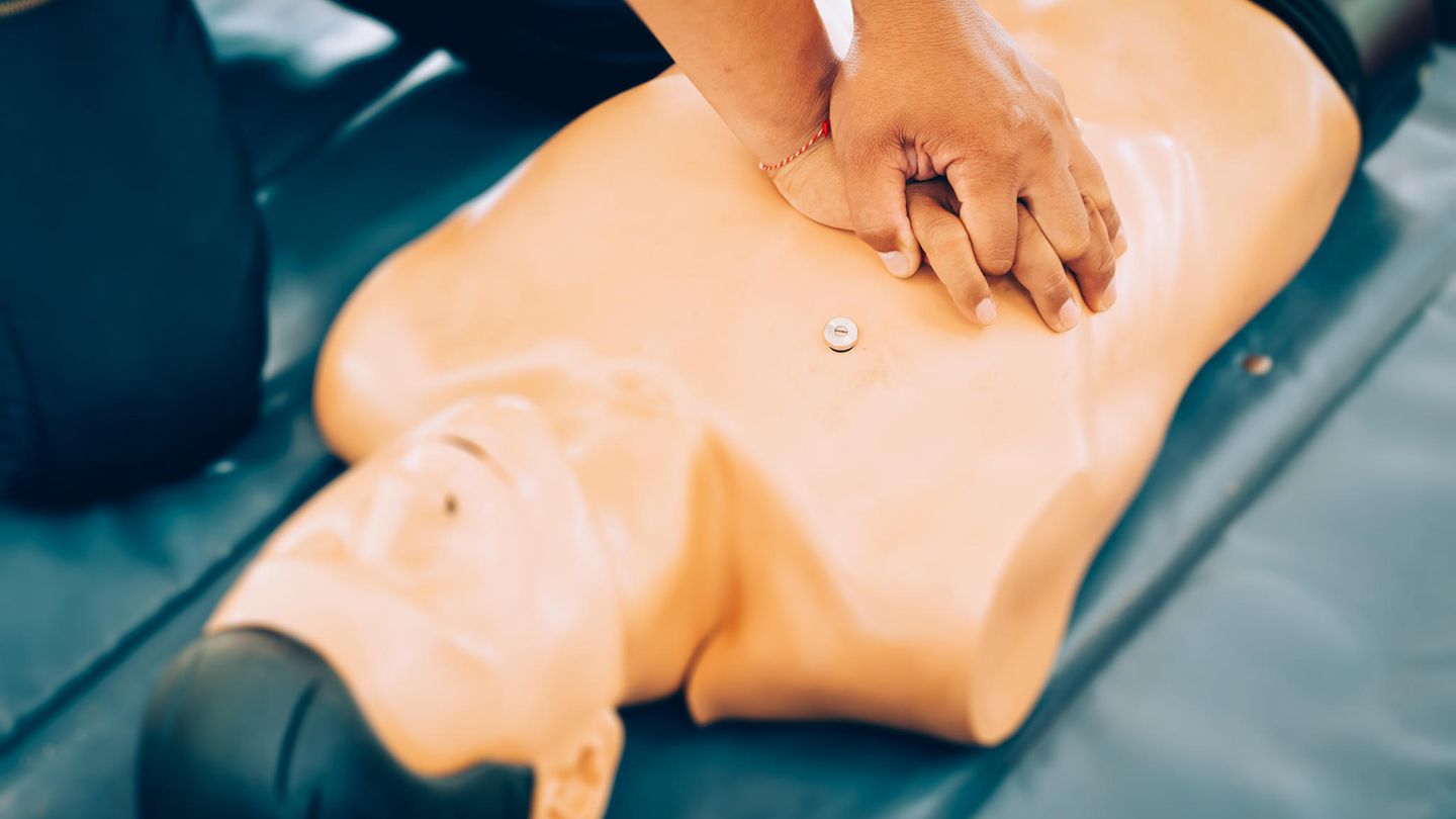 Ein Mann, der an einer Puppe eine Herzdruckmassage übt