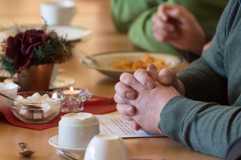 Ein Mann sitzt mit gefalteten Händen an einem Tisch im "Restaurant des Herzens" der Evangelischen Stadtmission Erfurt