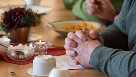 Ein Mann sitzt mit gefalteten Händen an einem Tisch im "Restaurant des Herzens" der Evangelischen Stadtmission Erfurt