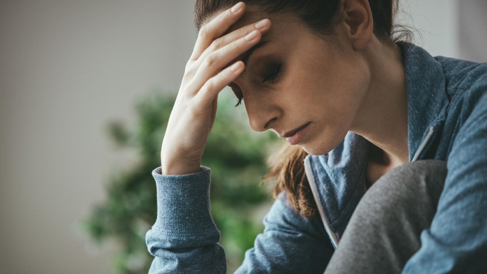Burnout im Privatleben: Eine Frau ist erschöpft und fasst sich an den Kopf