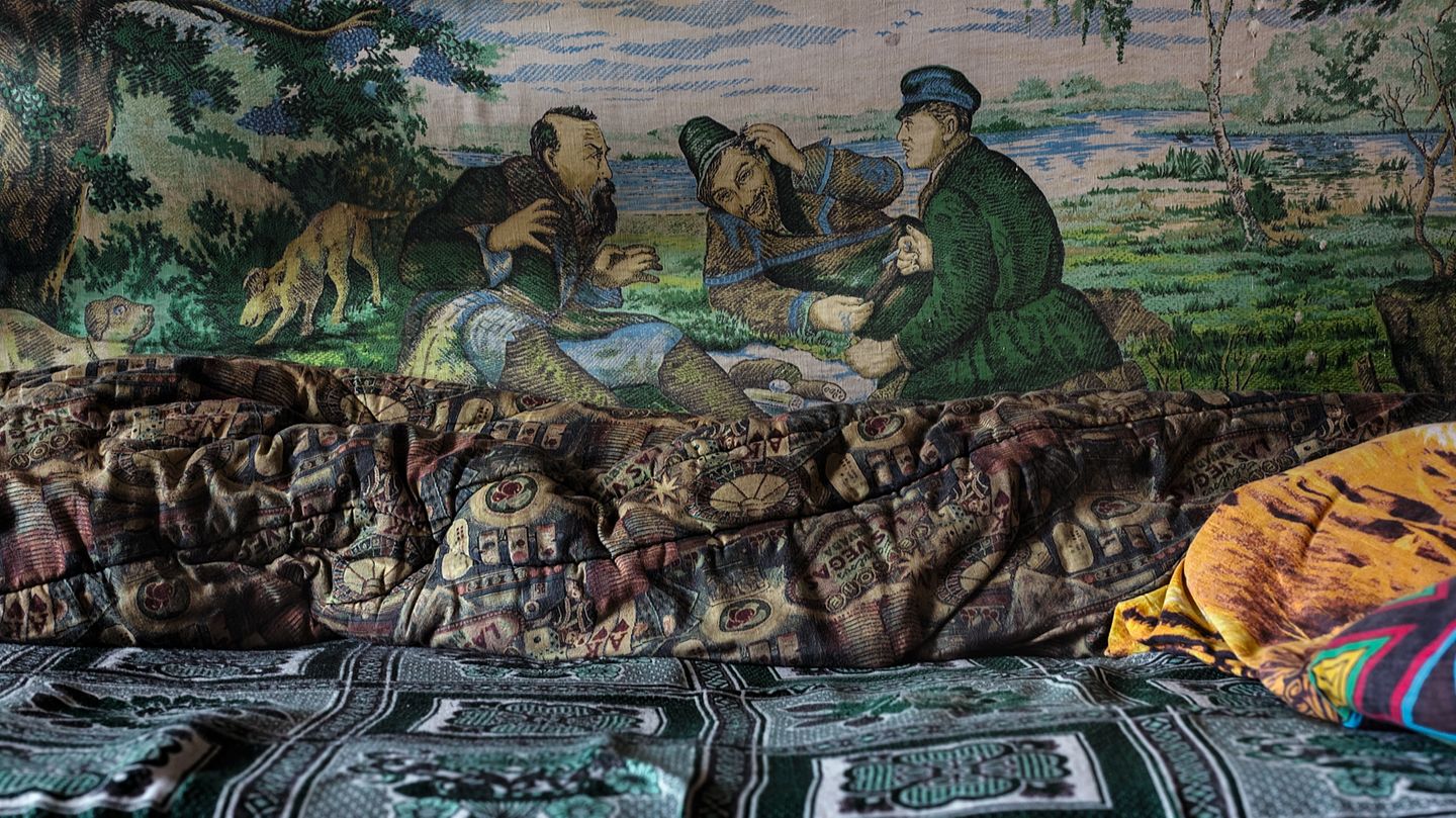Eine Schlafstelle, an der Wand die Reproduktion eines berühmten russischen Gemäldes des 19. Jahrhunderts: "Jäger auf Rast" von Wassilij Perow.