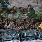 Eine Schlafstelle, an der Wand die Reproduktion eines berühmten russischen Gemäldes des 19. Jahrhunderts: "Jäger auf Rast" von Wassilij Perow.