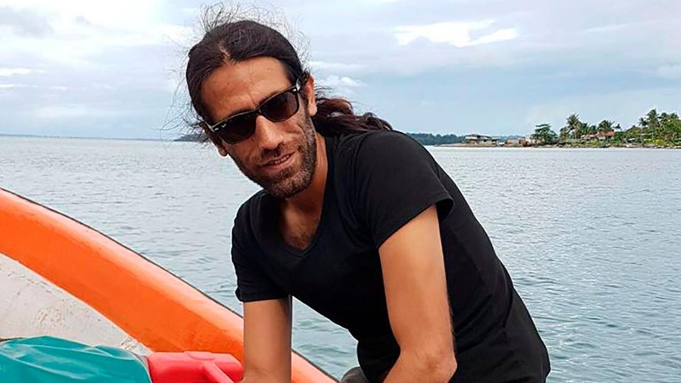 Behrouz Boochani sitzt lächelt auf einem Boot