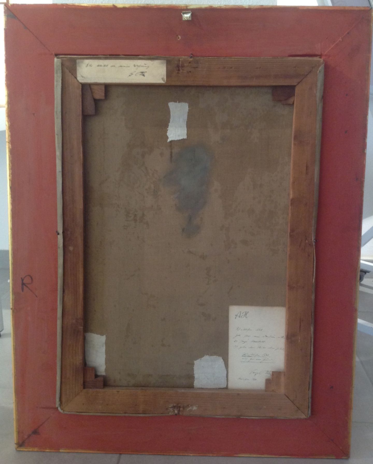 Interessant ist auch die Rückseite des Gemäldes. Kujau beschädigte absichtlich die Leinwand an drei Stellen, um sie auf der Rückseite auffällig zu flicken. Und auf der Bildrückseite sind zwei Zettel mit Hitlers Schrift angebracht.  Zettel oben links: "Bild bleibt in meiner Wohnung AH"