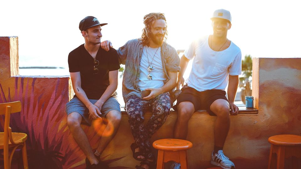 Drei Männer sitzen auf einer Mauer