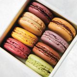 Schokoladen-Macarons      Zutaten:  Für die Baiserkekse: 100 g Mandelmehl, so fein wie möglich, 3 EL (15 g) ungesüßtes Kakaopulver, 3 große Eiweiß, ¼ TL feines Meersalz, ⅛ TL Weinsteinpulver, 50 g feinster Zucker, 150 g Puderzucker  Für die Ganachefüllung: 115 g hochwertige Zartbitterschokolade (60–70 % Kakaogehalt), fein gehackt, 80 g Schlagsahne, 15 g Butter, gewürfelt      Zubereitung:  Für die Baiserkekse: Die Backgitter in das untere und das obere Drittel des Backofens geben und den Backofen auf 100 °C vorheizen. Zwei Backbleche mit Backpapier oder Backmatten aus Silikon auslegen. Darauf achten, dass die Backbleche und die Backmatten trocken sind. Das Mandelmehl und das Kakaopulver in eine Schüssel sieben. Die groben Mandelstücke, die nicht durch das Sieb fallen, entfernen.  In einer mittelgroßen Schüssel das Eiweiß, das Salz und das Weinsteinpulver mit einem Handmixer bei niedriger Geschwindigkeit etwa 30 Sekunden schaumig schlagen. Die Geschwindigkeit auf die mittlere Stufe erhöhen und etwa 1 Minute, oder bis die Baisermasse weiche Spitzen bildet, weiterschlagen. Mit hoher Geschwindigkeit zu steifen Spitzen schlagen und währenddessen den Zucker in 4–5 Portionen mit je 15 Sekunden Abstand einstreuen. Die Baisermasse soll glänzend und weiß sein. Langsam den Puderzucker dazugeben und bei niedriger Geschwindigkeit weiterschlagen, bis die Spitzen wieder steif sind.  Das gesiebte Mandelmehl und das Kakaopulver mit kreisenden, vertikalen Bewegungen unterheben, um die luftige Konsistenz der Baisermasse zu erhalten. Der Teig sollte wie ein Band von dem Spatel fließen.  Den Macaronteig in einen Spritzbeutel mit einer runden, 1,25 cm großen Spritztülle füllen. Den Spritzbeutel senkrecht über das Backblech halten und Kreise mit einem Durchmesser von 4 cm und mit einem Abstand von 4 cm auf das Backblech spritzen. Auf jedes Blech sollten etwa 30 passen. Das Backblech einige Male auf die Arbeitsfläche schlagen, um die Luftbläschen zu entfernen.  12–16 Minuten, oder bis die Macarons eine Wölbung bekommen haben, backen und nach 10 Minuten die Backbleche umdrehen und das obere mit dem unteren tauschen. Um zu prüfen, ob die Macarons fertig sind, ein paar Kekse sanft hin und her rücken. Wenn sich dabei der obere Teil bewegt, müssen sie noch ein wenig länger gebacken werden. Wenn sie nicht nachgeben, sind sie fertig.  Ein paar Minuten auf dem Blech auskühlen lassen und dann vorsichtig abheben und auf einem Gitter komplett auskühlen lassen.      Für die Ganachefüllung: Die Schokolade in eine hitzebeständige mittelgroße Schüssel geben. In einem kleinen Topf die Sahne aufkochen. Über die Schokolade gießen und mit einem Spatel verrühren (ohne sie zu verschlagen), bis die Masse glatt ist und glänzt. Die Butter dazugeben und verrühren, bis sie eingearbeitet ist. Den Spritzbeutel und die Tülle reinigen und die Ganache hineinlöffeln. 30 Minuten auskühlen lassen.      Anrichten: Baiserkekse ähnlicher Größe paaren. Einen Klecks Ganachefüllung, etwa 1 gehäufter TL, auf einen Keks aller Paare spritzen. Den jeweils dazugehörenden leeren Keks daraufsetzen, andrücken und sanft hin und her drehen, um die Füllung gleichmäßig zu verteilen. Damit sie fest werden, mindestens 2 Stunden oder über Nacht kalt stellen. 146 ~