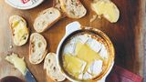 Gebackener Camembert mit Honig & Cidre      Zutaten:  220–250 g Camembertkäse, 1 EL Cidre oder Apfelweinbrand, z. B. Calvados, 2 TL Honig, frisches Baguette zum Servieren      Zubereitung:  Den Käse 1 Stunde im Voraus aus dem Kühlschrank holen. Aus der Verpackung nehmen und jegliche Aufkleber oder Etiketten entfernen. Den Käse in eine ofenfeste Schüssel oder Backform, die weder zu groß noch zu klein ist, geben. Den Backofen auf 200 °C vorheizen. Mit einem scharfen Messer den Camembert in einem Rautenmuster tief einritzen. Mit dem Cidre beträufeln und den Honig darauflöffeln. 15–20 Minuten, oder bis der Käse geschmolzen und angebräunt ist, backen. 5 Minuten ruhen lassen und dann mit dem Brot servieren.