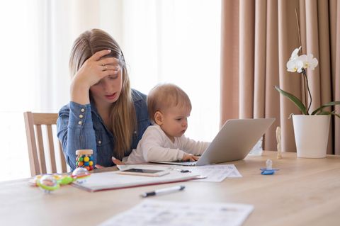 Eine Mutter am Laptop mit Baby auf dem Schoß