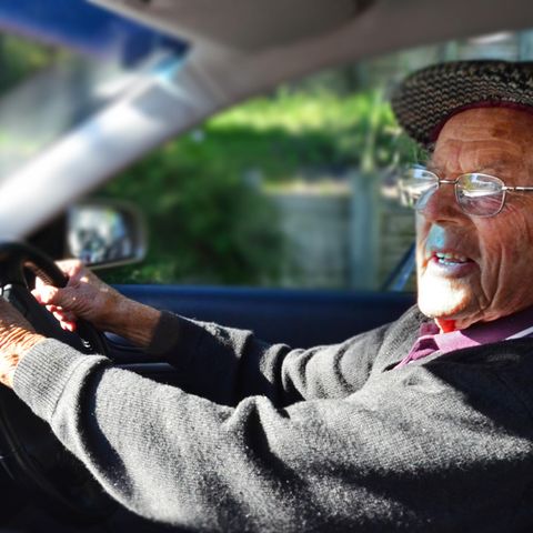 Älterer Herr fährt Auto und hat die Hände am Lenkrad